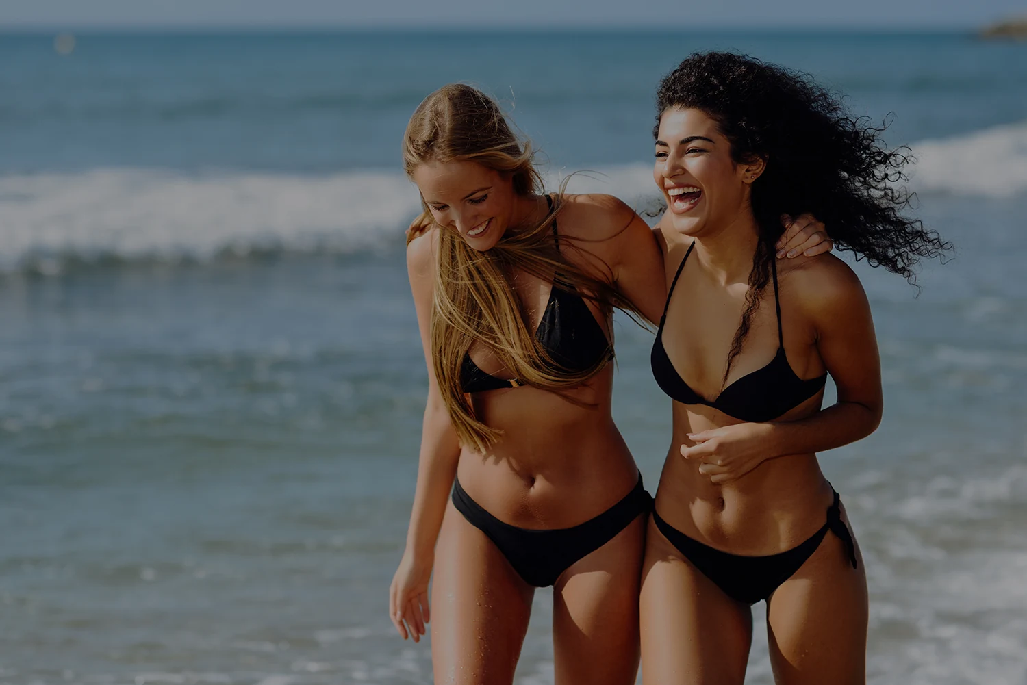 two friends in swimsuit walking down the beach